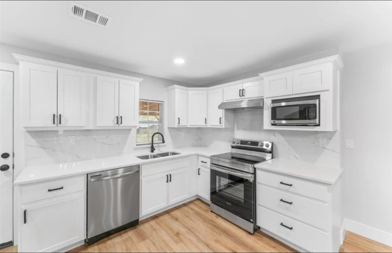 Modern Dallas kitchen remodel with white shaker cabinets, marble backsplash, and stainless steel appliances