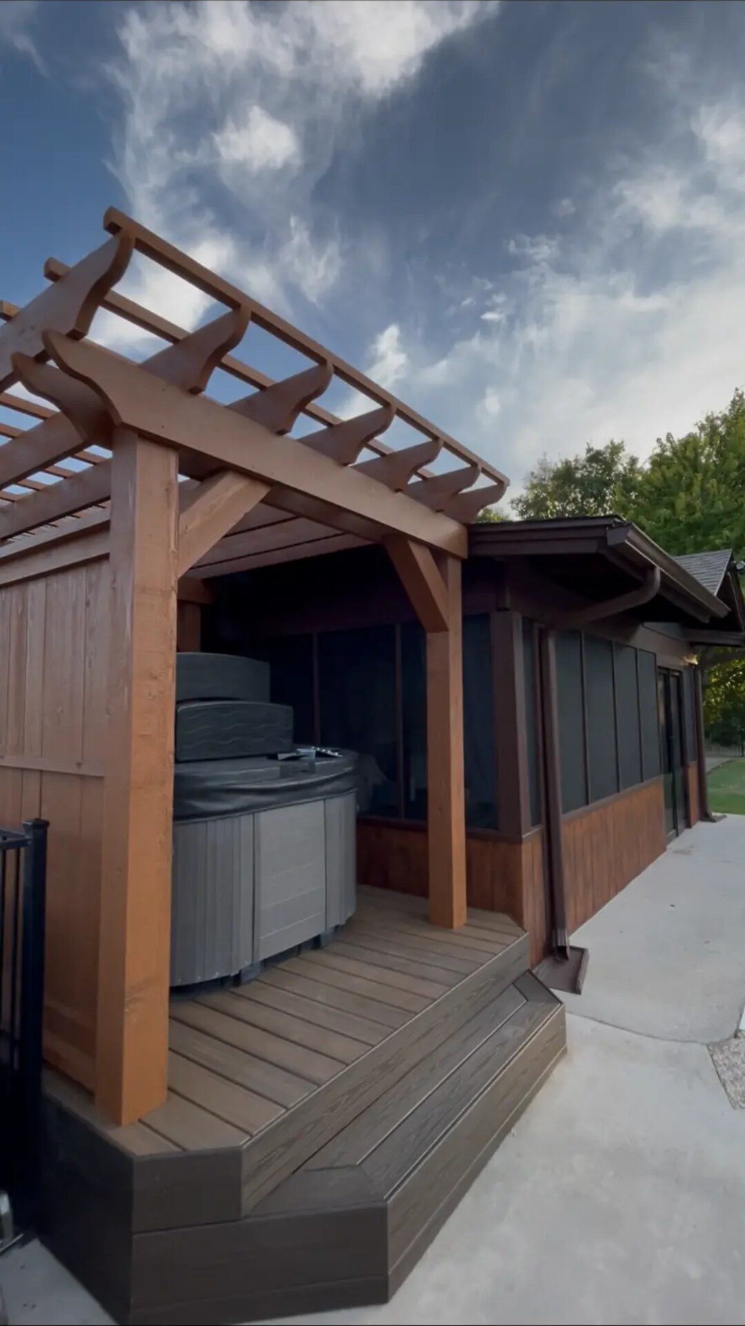 Custom outdoor living space with a stained wood pergola, hot tub, and deck overlooking a Dallas-area backyard