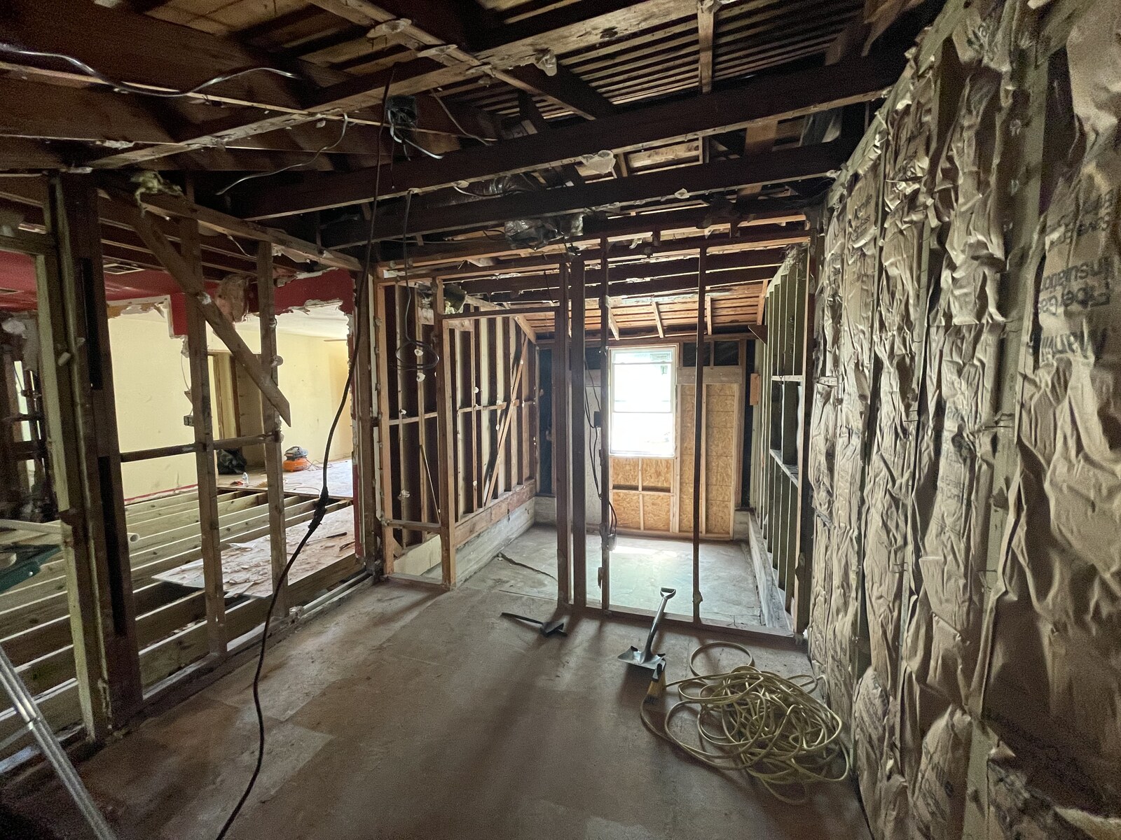 Full gut remodel in progress with exposed wall studs, ceiling joists, and insulation during demolition